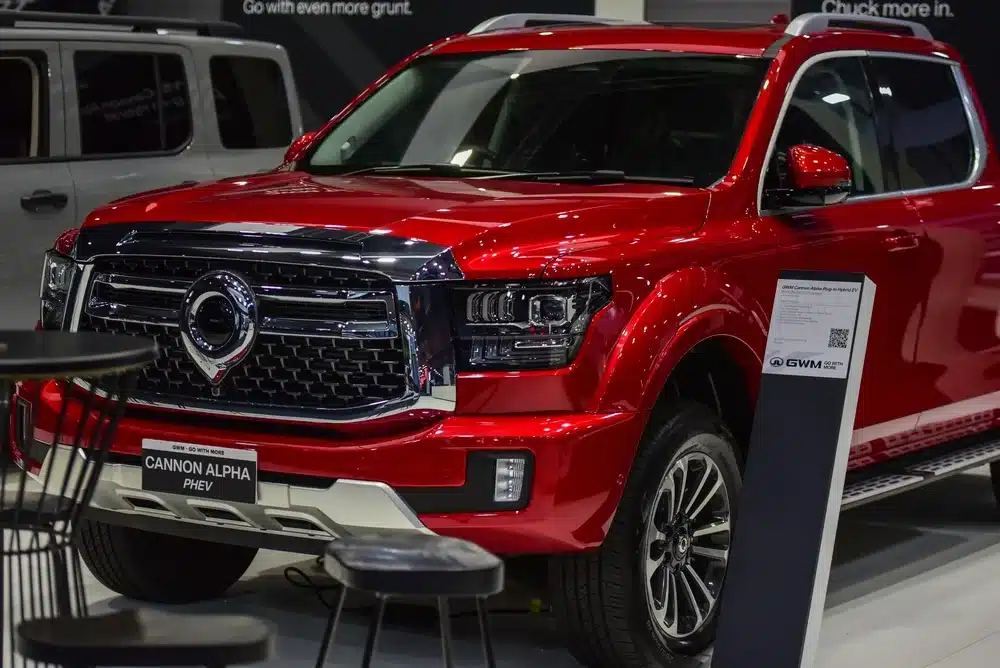 Red GWM Cannon Alpha PHEV displayed in a showroom with front grille and headlight details